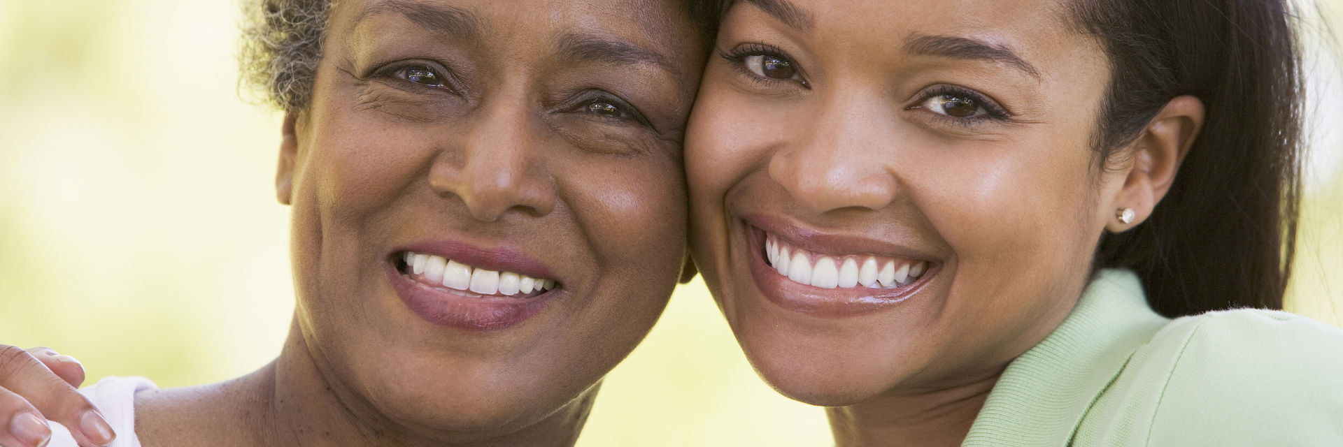 A senior Afro-American woman and her daughter showing perfect teeth in their smiles.
